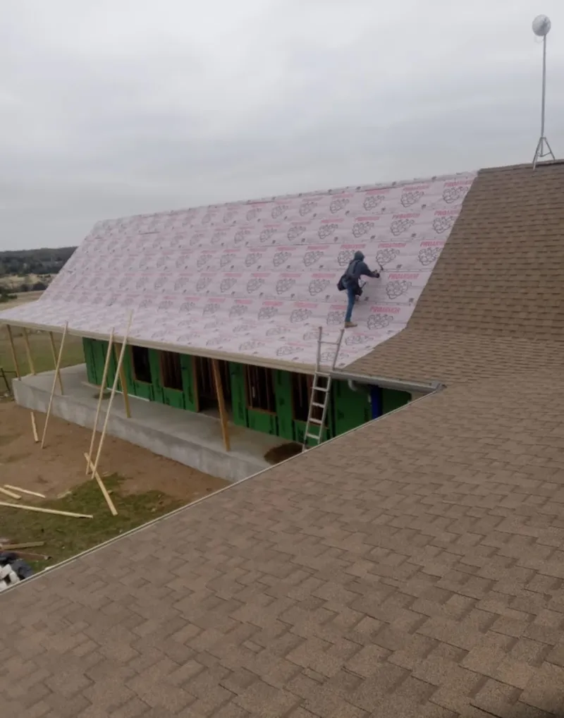 Worker preparing underlayment for a metal roof installation in Maumee